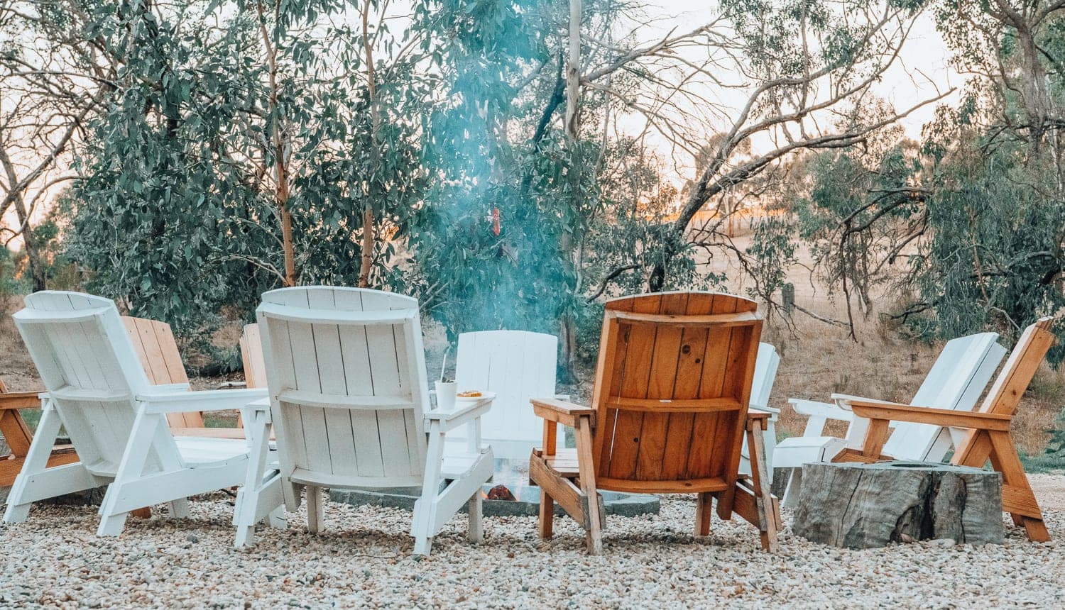 Chairs around the fire pit by day, smoke drifting through the trees