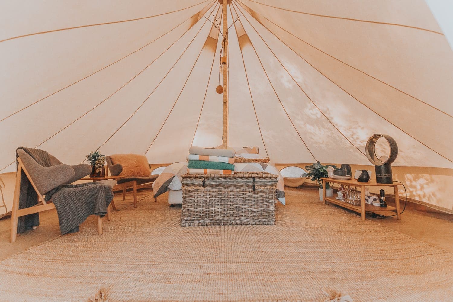 The full tent interior — queen bed, lounge chairs and a timber chest on the rug