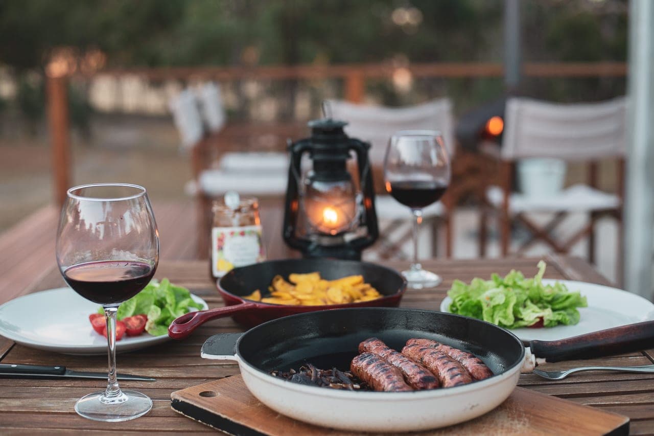 A lantern, red wine and dinner on the camp kitchen table