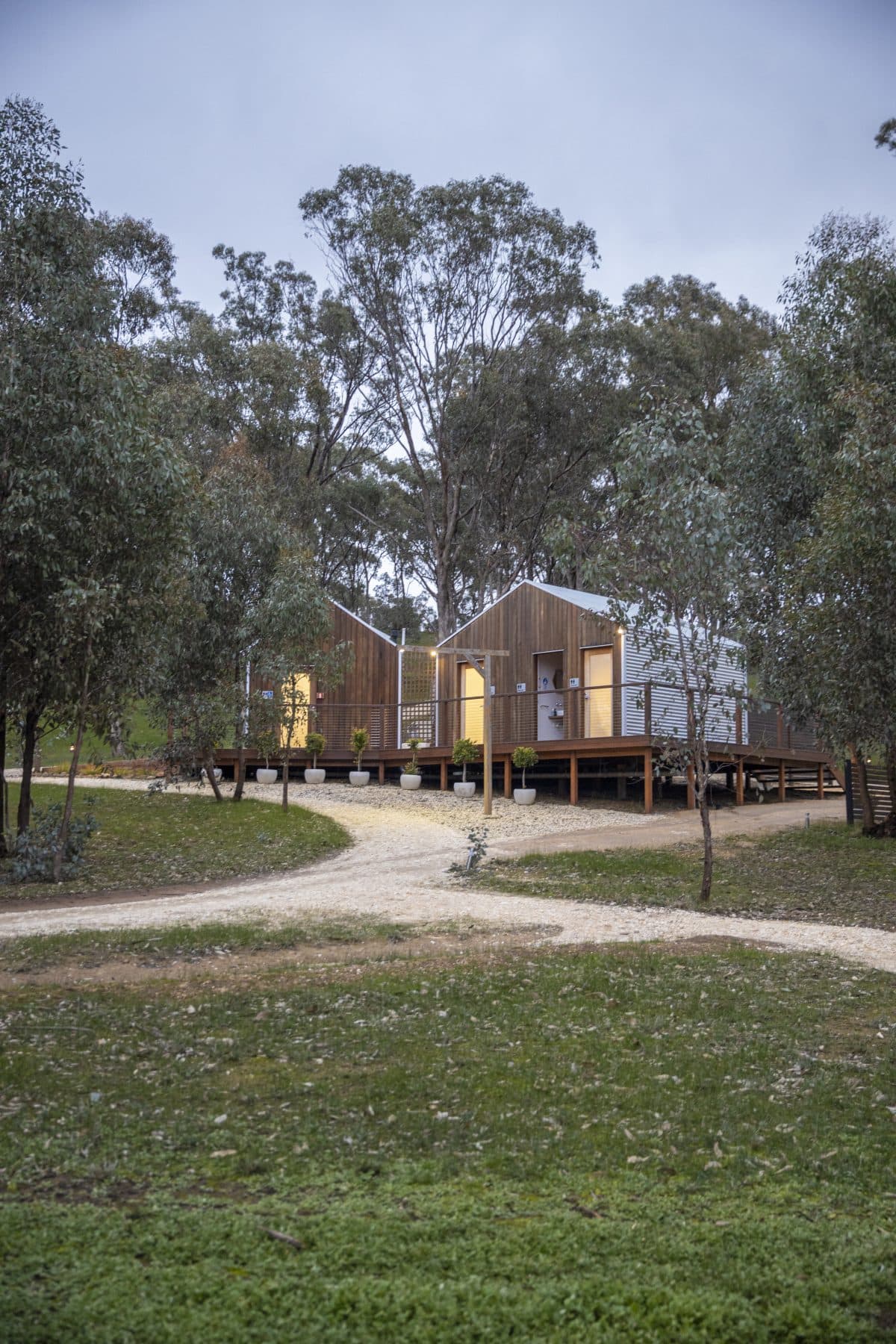 Two A-Frame cabins on the gravel path through the gums