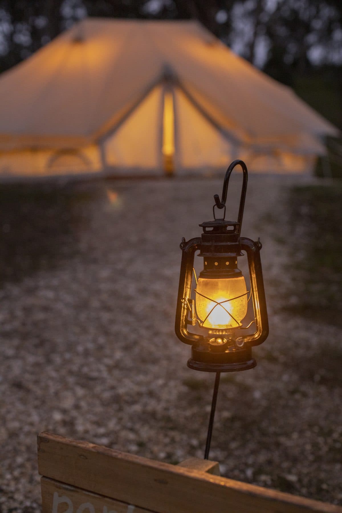 A lantern lit at dusk outside a bell tent