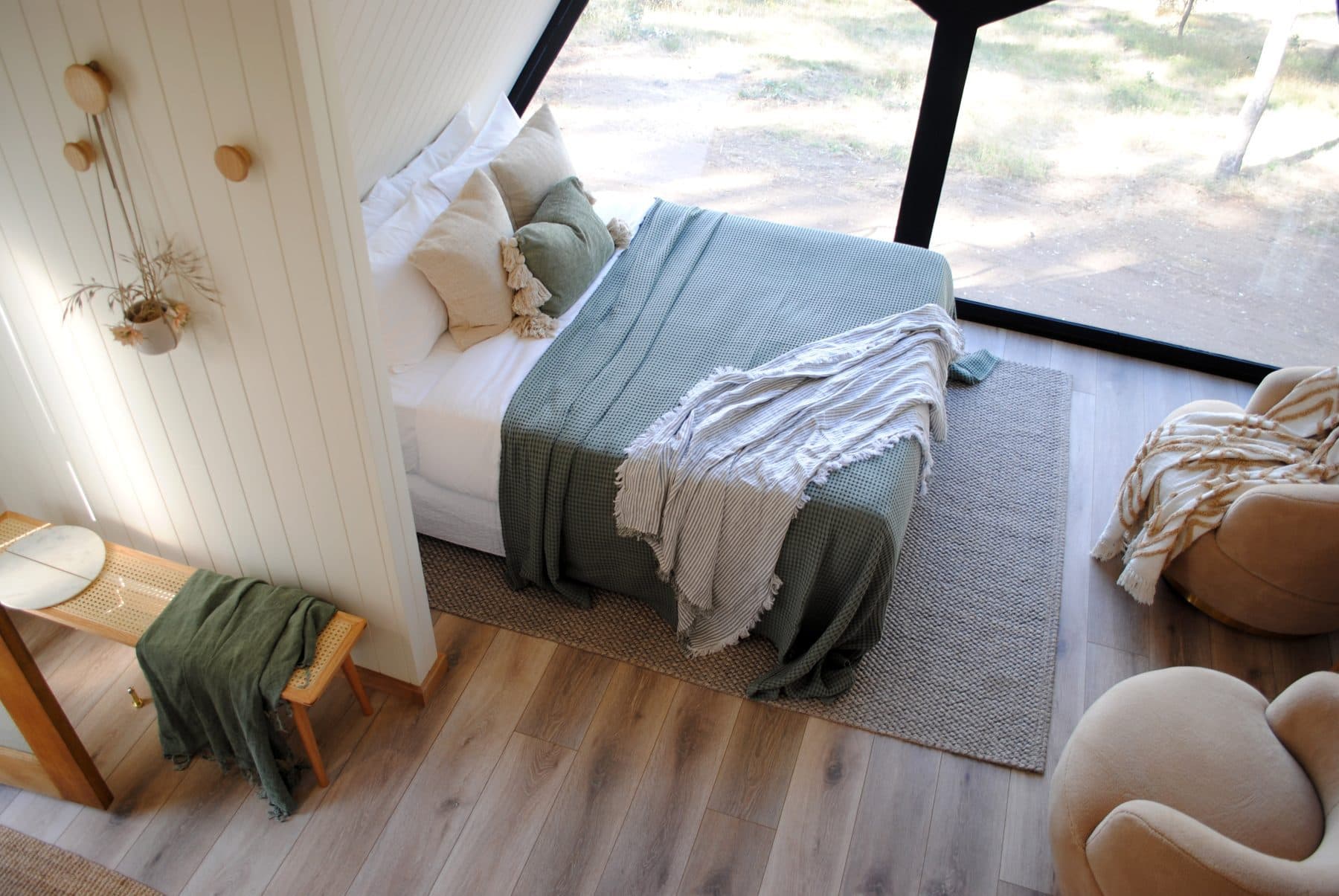 The cabin bed beside the full-height window, a sage throw folded on top