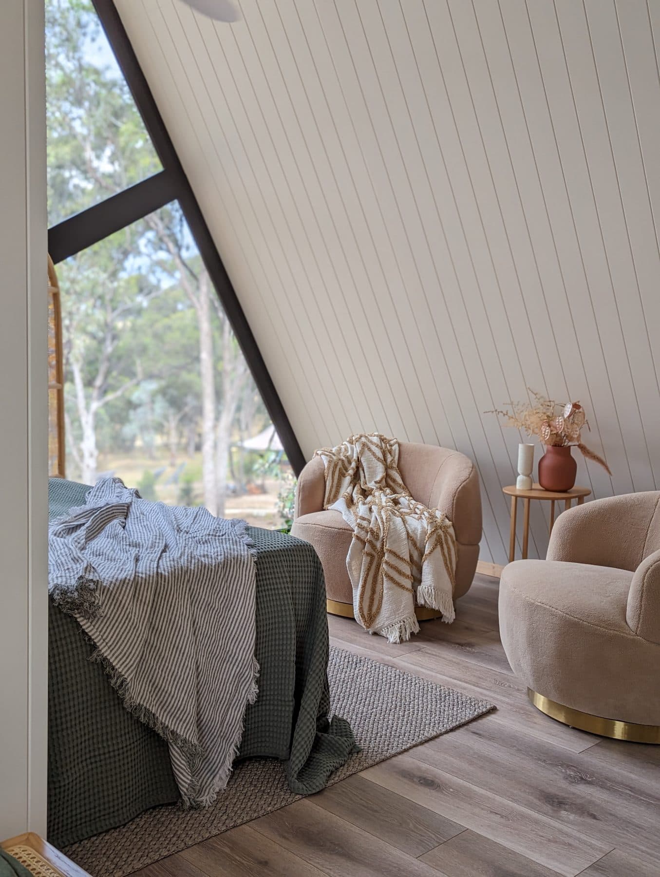 An armchair and side table inside the cabin, the gable window behind
