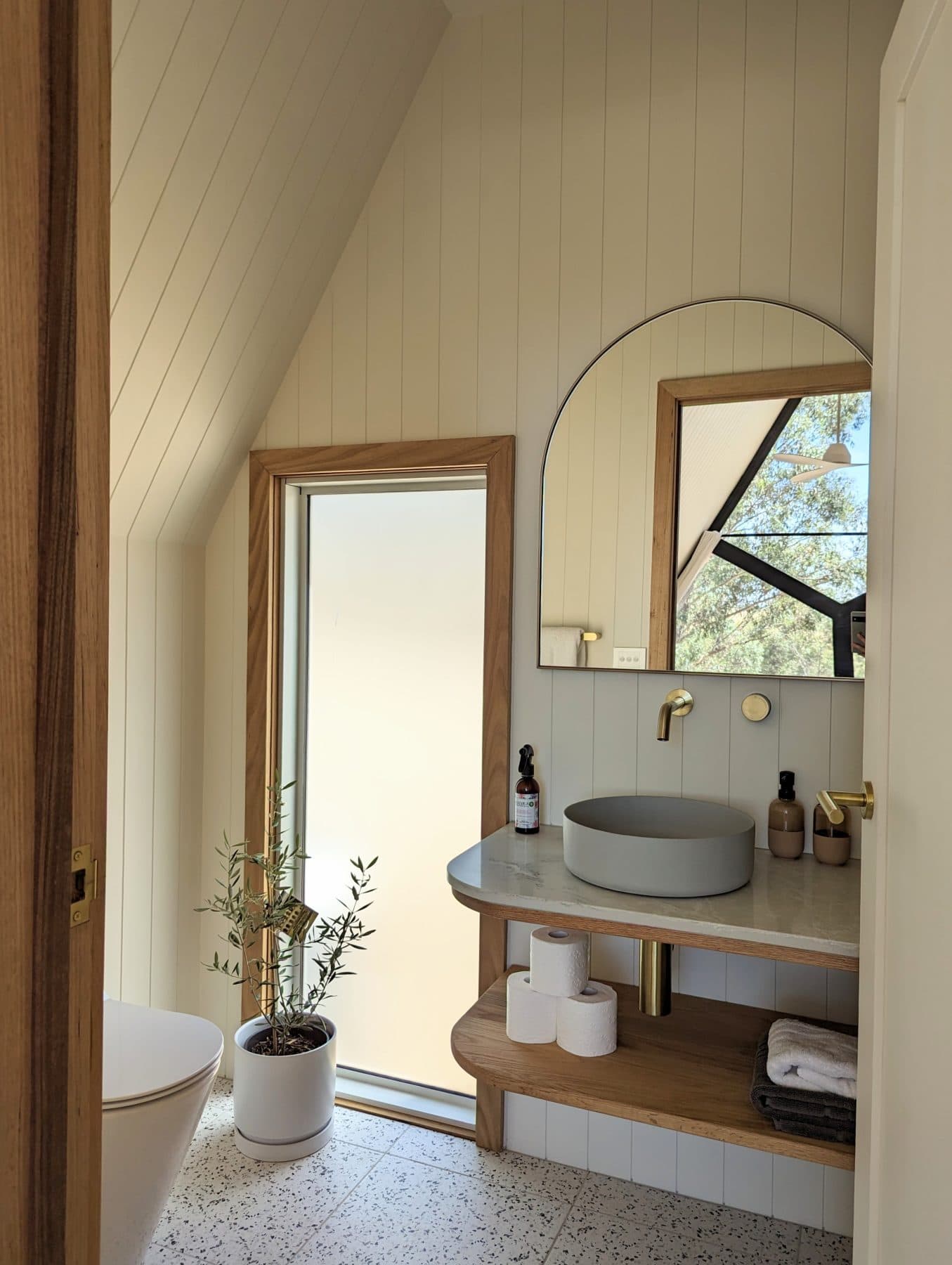 The private ensuite: a round basin, a mirror and a window to the trees