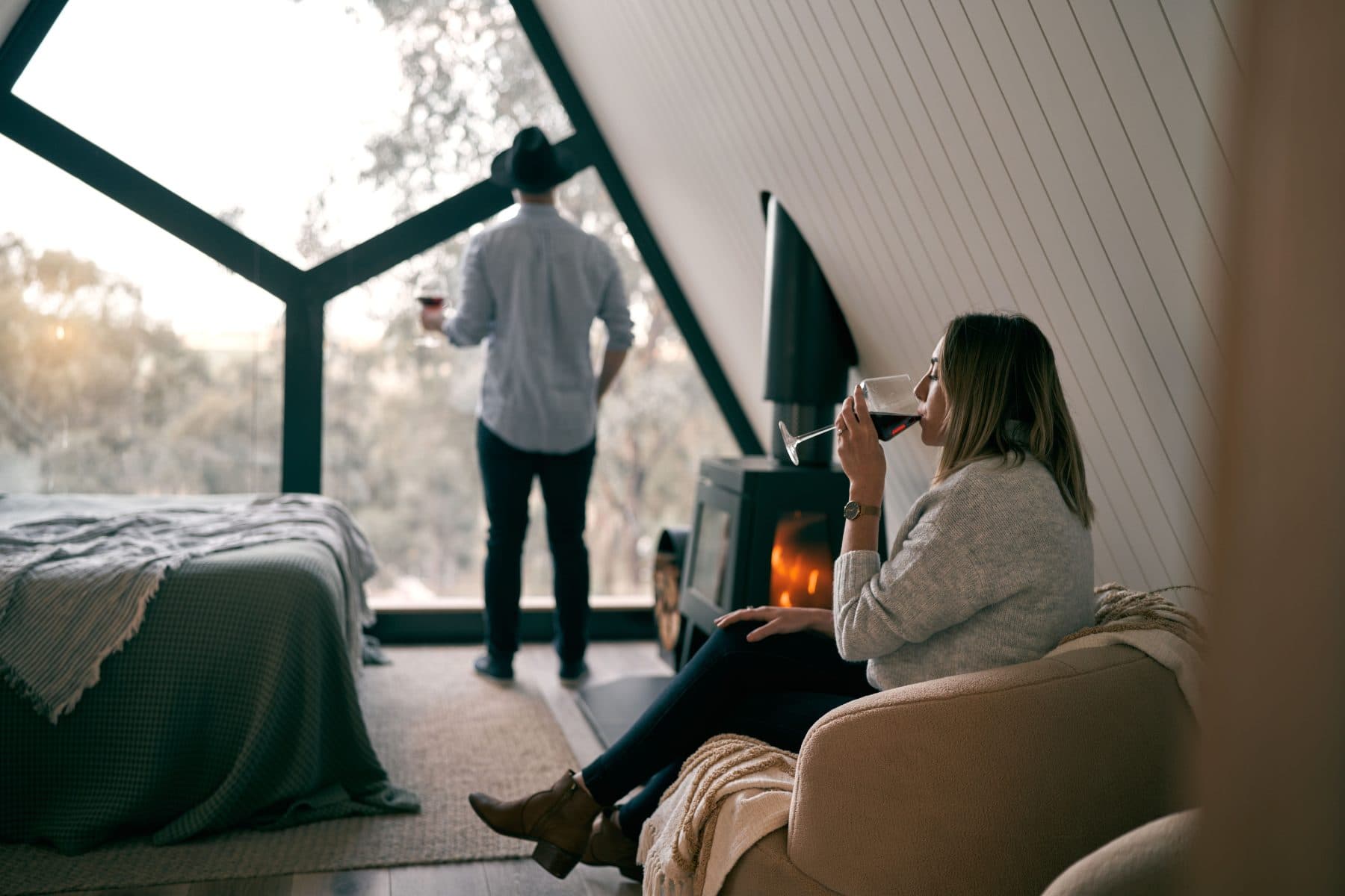 A couple inside the cabin at the window, drinks in hand