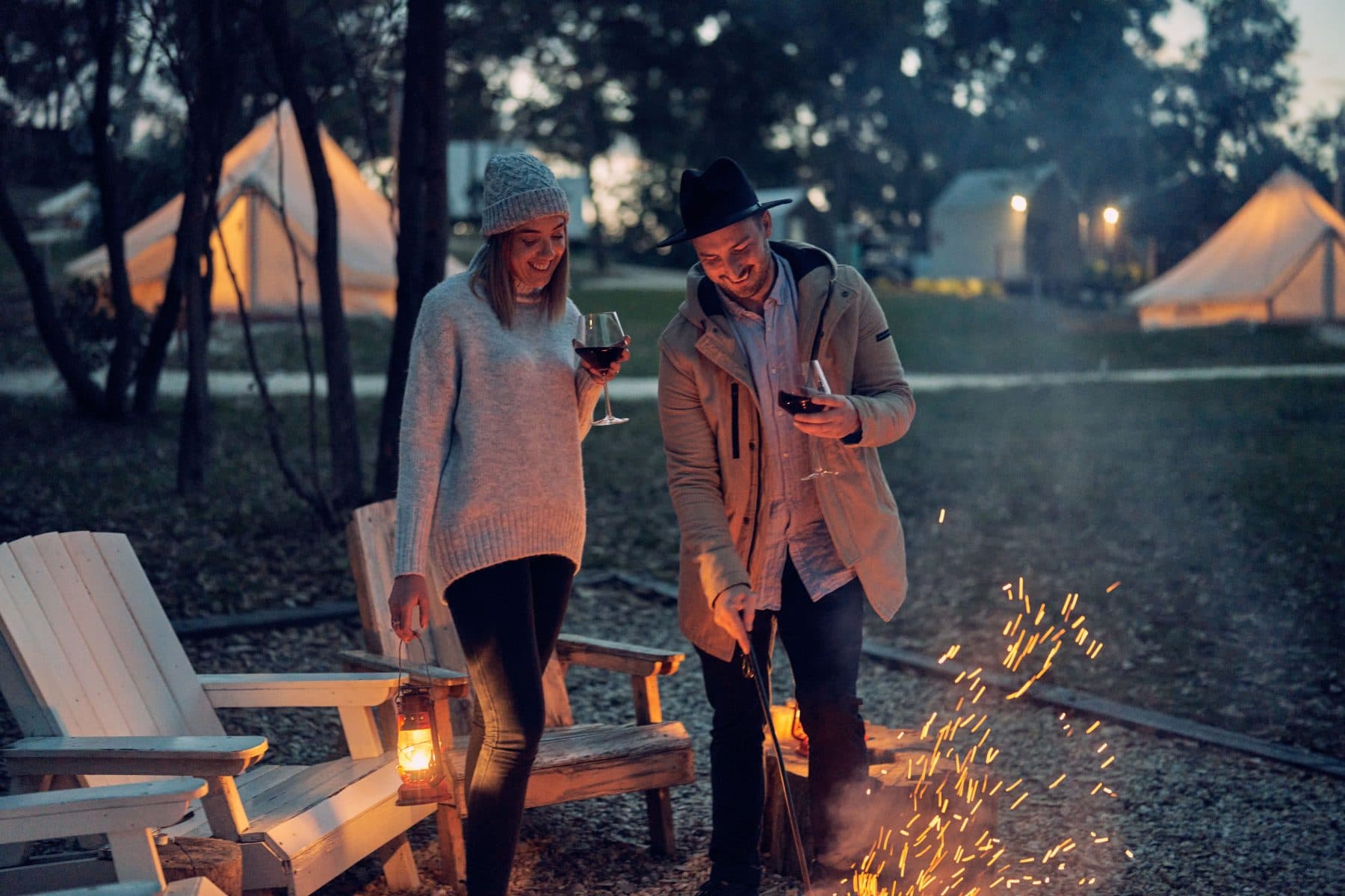 Two guests with a glass of wine beside the fire pit, sparks rising