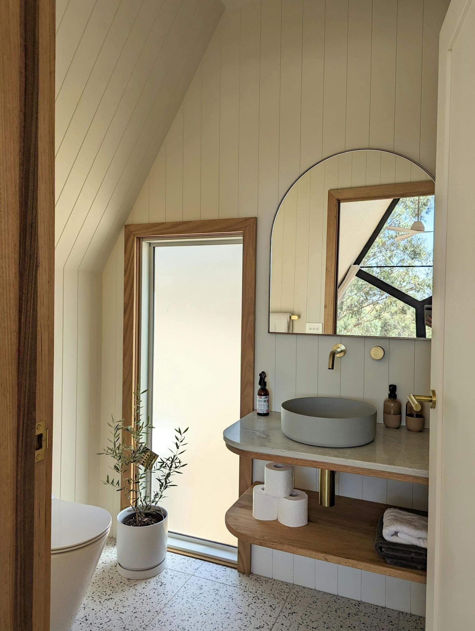 The private ensuite: a round basin, a mirror and a window out to the trees