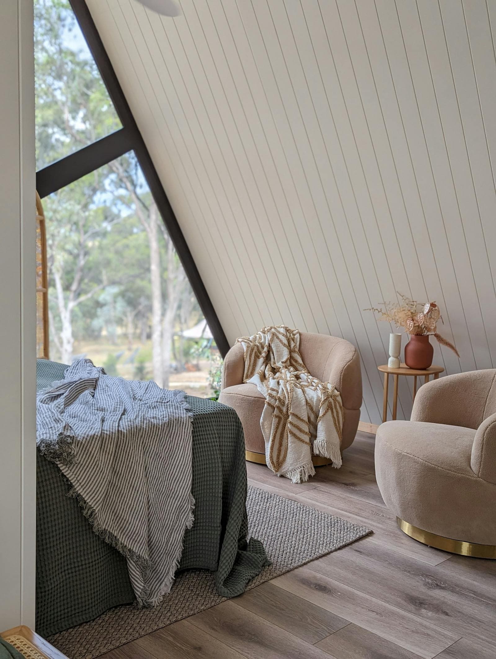 The bed and an armchair in the cabin, morning light through the gable window