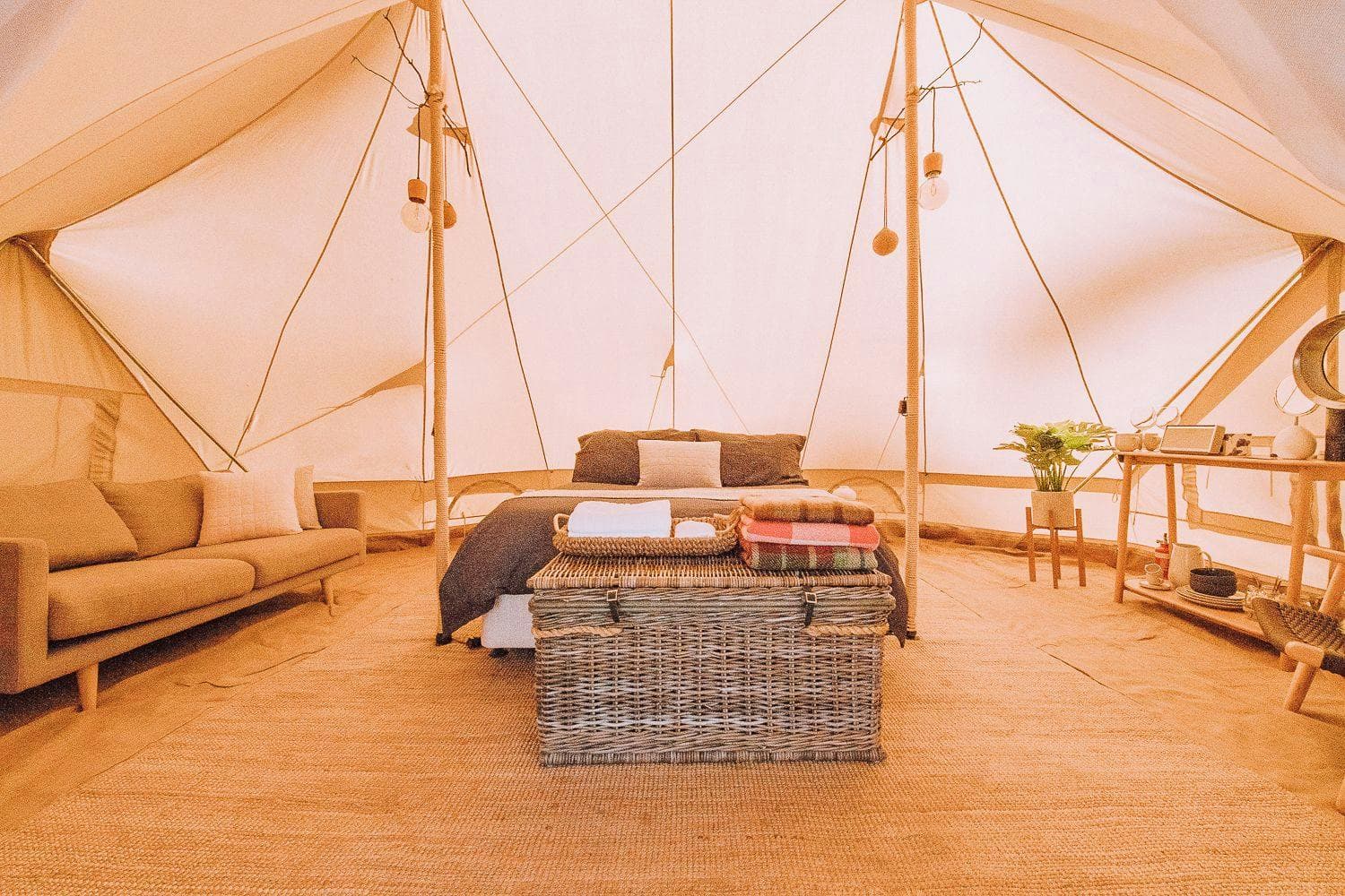The full Luxe interior — queen bed, two lounge chairs, a chest and a woven basket on the rug