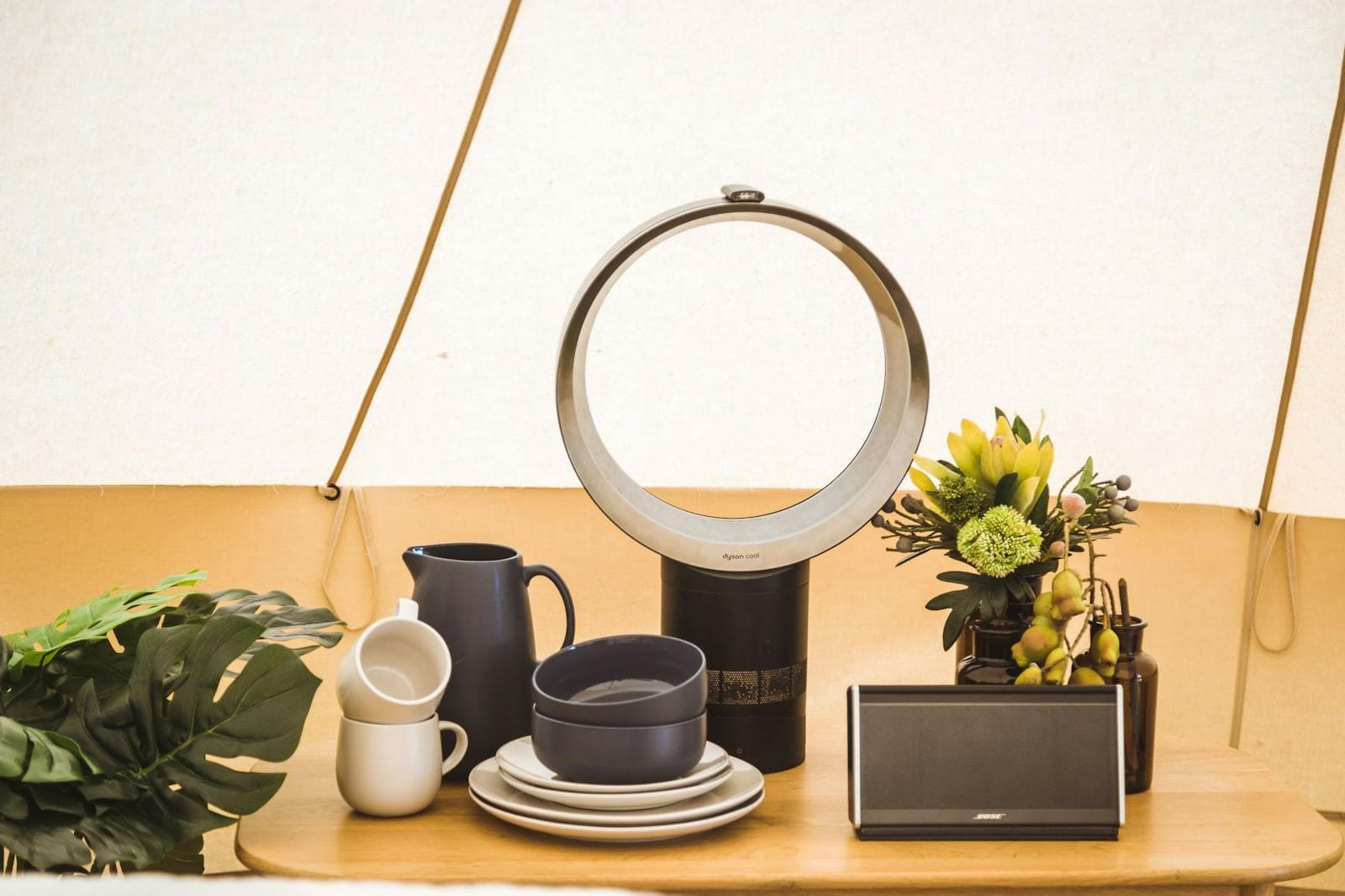 Inside a Luxe tent: the Dyson fan, a Bose speaker, mugs and crockery on the side table