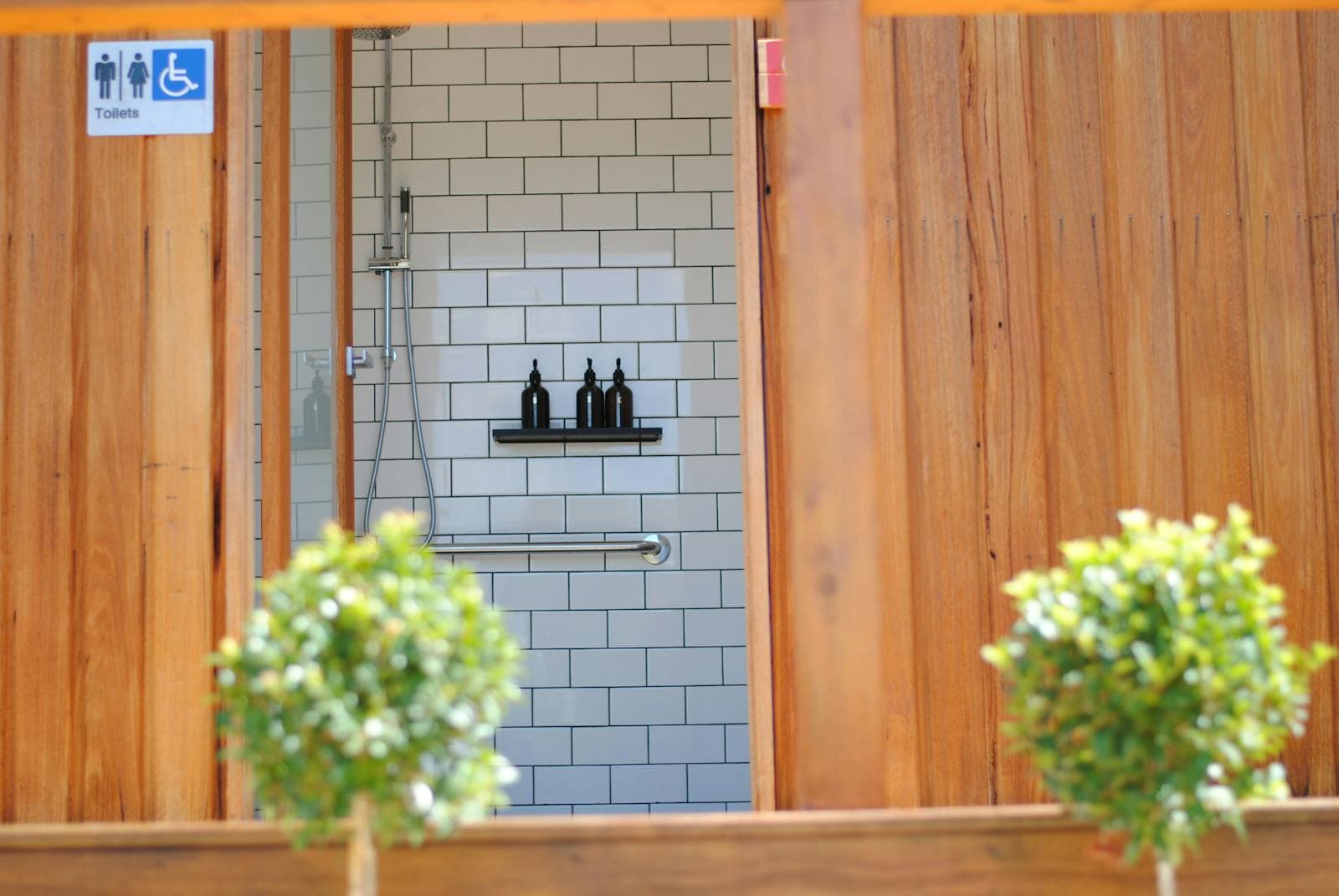 The entrance to the bathroom block, timber-clad with pot plants either side