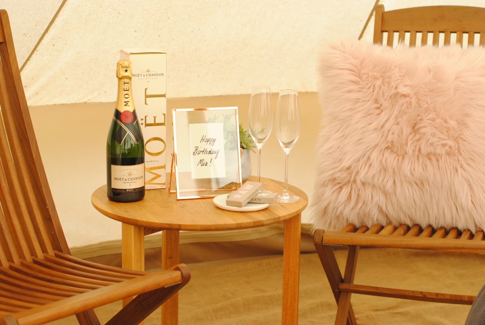 Moët Moments set up on a side table inside a bell tent: the bottle, two flutes, chocolates and a framed message