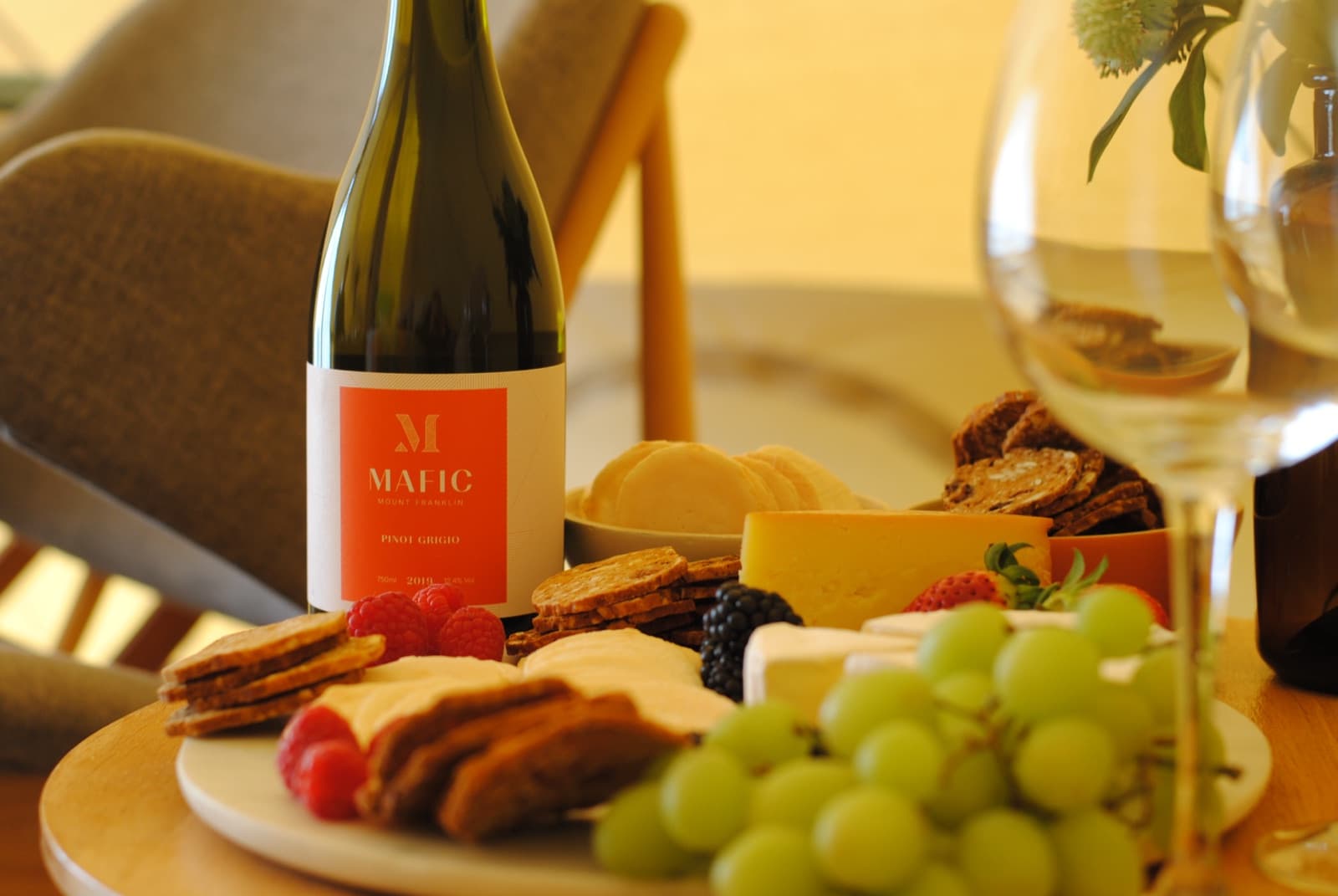The Wine & Cheese package: a bottle of Mafic pinot grigio, two glasses, cheeses, crackers, grapes and strawberries on a board
